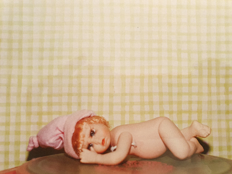 poupée en porcelaine sur le ventre bonnet rose